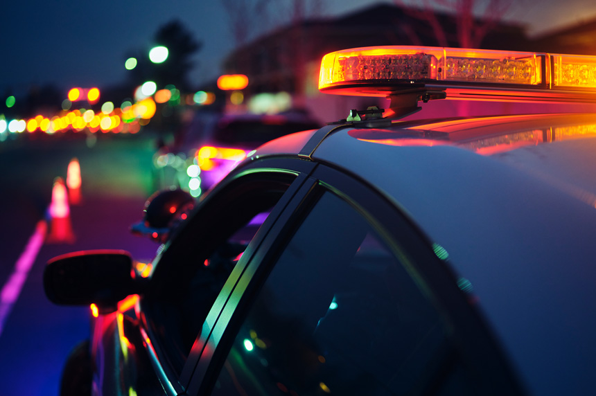 Police vehicle driving down a colorfully lit street representing OSINT law enforcement investigation