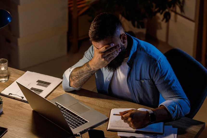 worker hiding his eyes at his desk