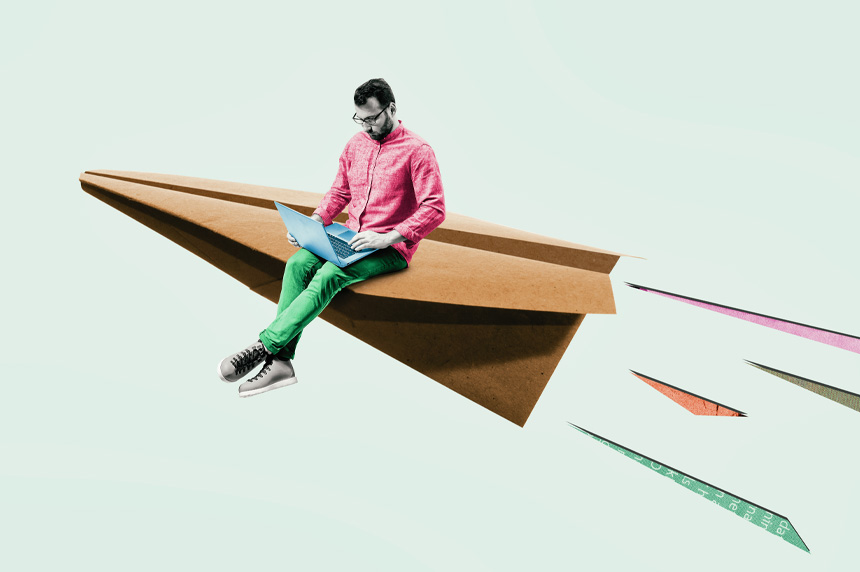 Man on laptop sitting on paper airplane