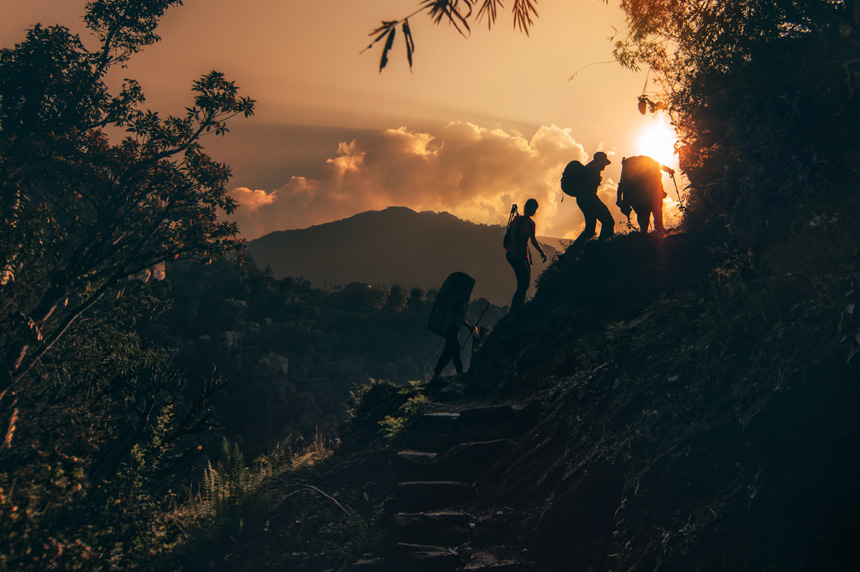 Men climbing up steps of a mountain with sunrise in the background