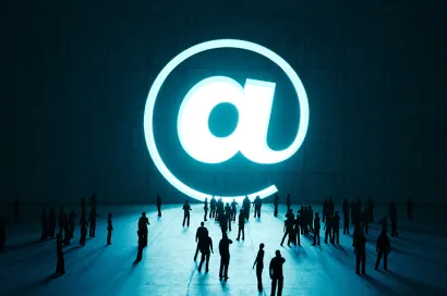 a group of people looking at a large @ symbol representing email