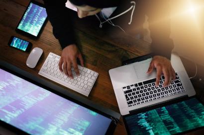 Person working on multiple monitors and laptops